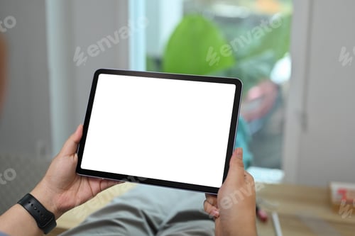 Preview: Close up view of hands holding holding digital tablet while sitting in living room.