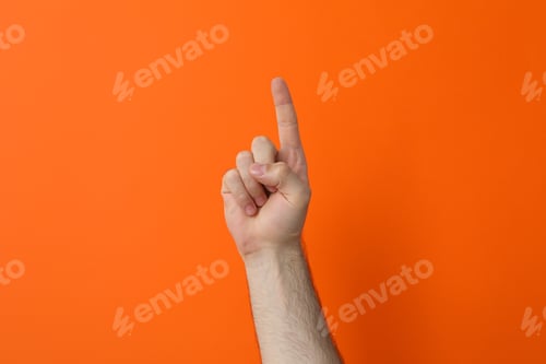 Preview: Male hand showing index finger on orange background