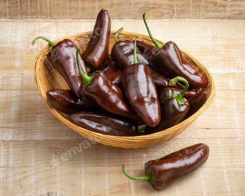 Preview: Basket with whole fresh chocolate mini pointed bell peppers close up