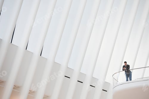 Preview: A person standing alone in an atrium by a railing, alone in a large space.