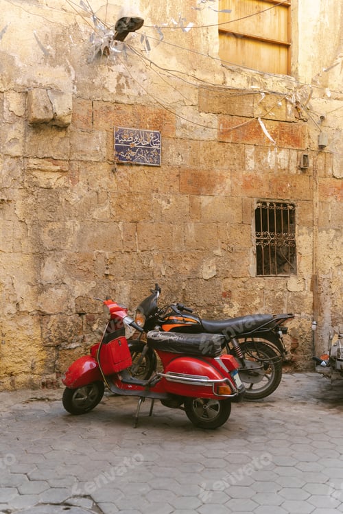 Preview: Red scooter parked next to old stone wall in cairo