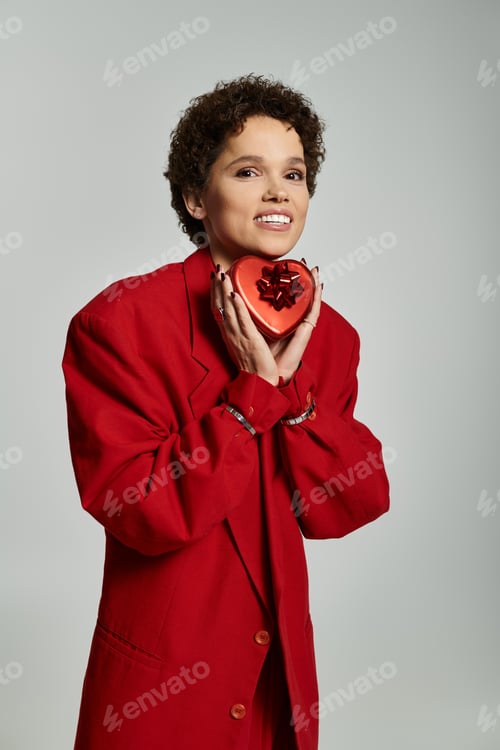 Preview: Bright smile and vibrant style embody joy with a heart shaped gift indoors