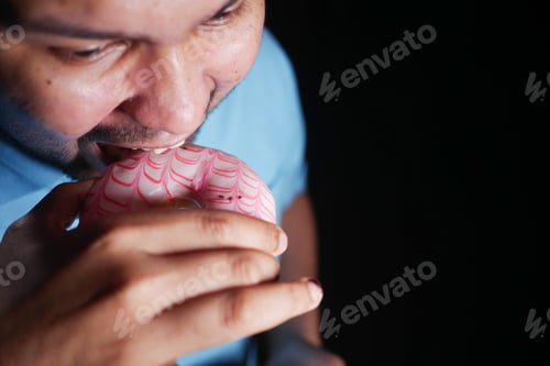 Preview: Man takes a bite of donut in low light setting