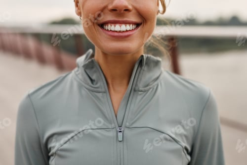Preview: A Smiling Young Woman in Athletic Wear Poses on an Outdoor Bridge, Radiating Joy
