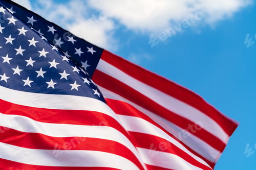 Preview: American flag waving in the wind against blue sky