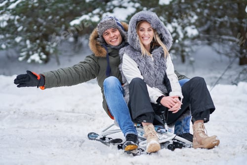 Preview: Couple having fun with sledge on snow in winter