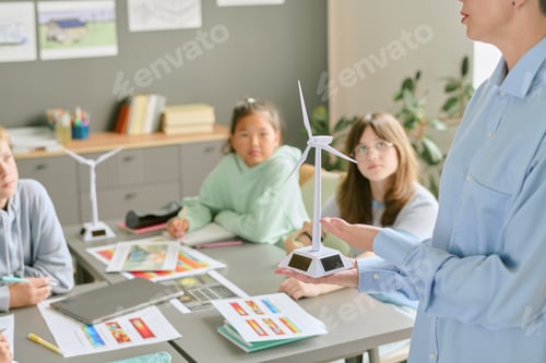Preview: Middle Aged Caucasian Woman Demonstrating Wind Turbine Model to Teenagers
