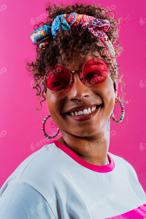 Preview: Young woman wearing rainbow t-shirt and pink sunglasses is smiling and looking away