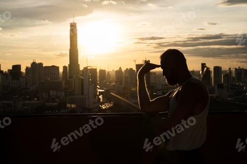 Preview: bearded brutal man enjoying sunset and view on Bangkok city