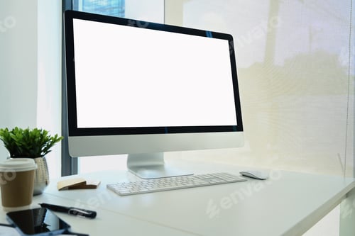 Preview: Comfortable workplace with blank screen computer monitor, paper cup and smartphone on white table
