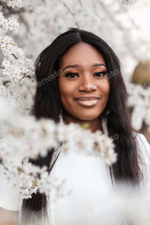 Preview: Emotional portrait of a beautiful black woman in flowers on nature in a spring day