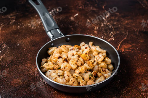 Preview: Fried peeled Shrimps prawns with garlic, olive oil in a skillet. Dark background. top view