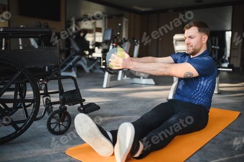Preview: Man with disability doing rehab exercises with medicine ball in gym