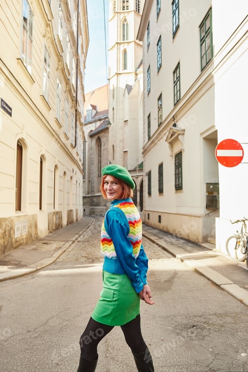 Preview: cheerful woman in beret and stylish clothes looking at camera on city street in Vienna, Austria
