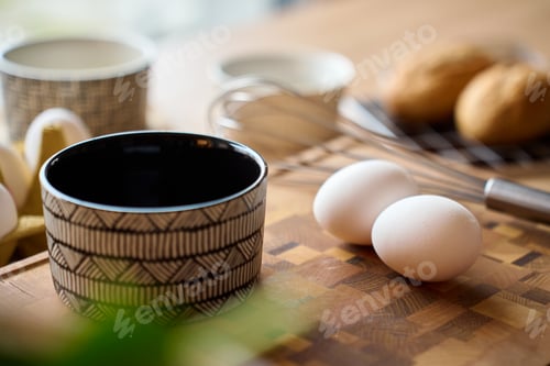 Preview: Eggs, whisk and ceramic bowl on wooden cutting board