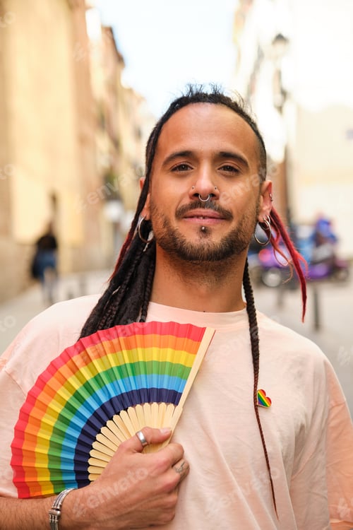 Preview: Gay man with a rainbow fan smiling and looking at camera.
