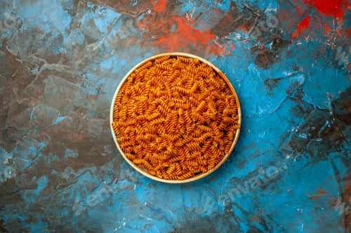 Preview: Top view of raw Italian pastas in a white bowl on blue background