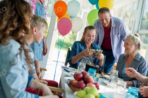Preview: A birthday party in a farmhouse kitchen, adults and children around a chocolate cake.