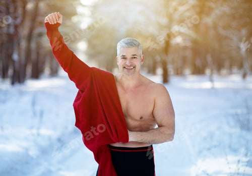 Preview: Cold exposure training and acclimation concept. Happy mature man taking off his warm clothes at