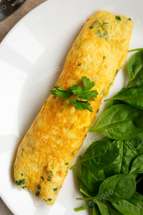 Preview: Homemade French Omelette with Fresh Herbs and Greens on a plate, top view. Flat lay, overhead