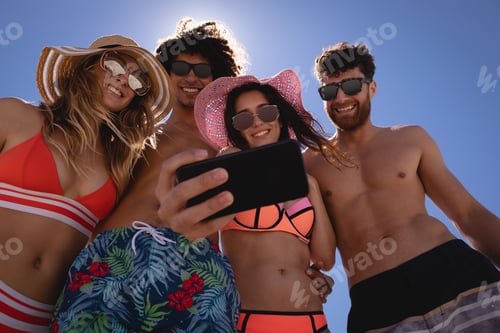 Preview: Friends taking selfie with mobile phone at beach in the sunshine