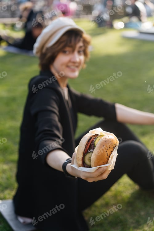 Preview: Girl enjoying takeaway burger in park