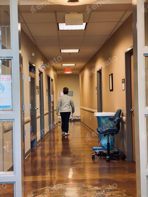 Preview: Looking down the hallway in a hospital as a nurse walks away from the waiting room.