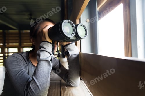 Preview: Young woman use of the binocular in wooden house