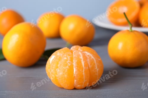 Preview: Peeled fresh ripe tangerine on grey wooden table, closeup