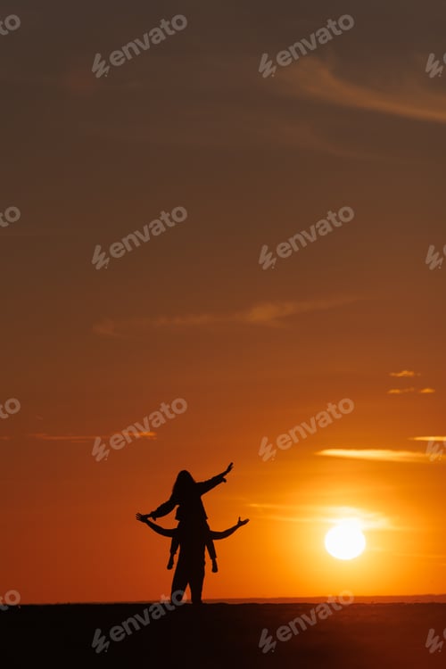 Preview: silhouettes of couple at sunset against bright sun and sky. man and woman have fun in nature
