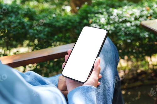 Preview: Mockup image of a woman holding mobile phone with blank white desktop screen in the outdoors