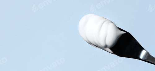 Preview: texture of cosmetic cream on a palette knife on a blue background