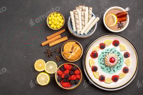 Preview: top view little yummy cake with lemon slices candies and cup of tea on dark background biscuit cake