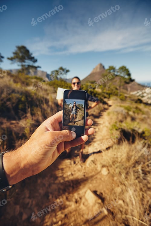 Preview: Man talking pictures of a woman with mobile phone - Hiking trip