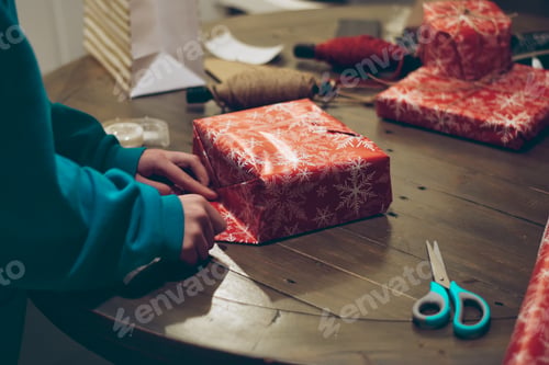 Preview: Young woman is wrapping Christmas presents