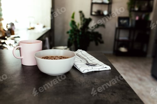 Preview: Pink coffee cup, chopped fruits in bowl blueberries, spoon on towel in kitchen