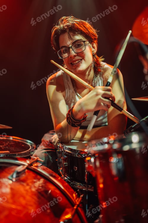 Preview: Drummer holding drumsticks and smiling at concert with red lights