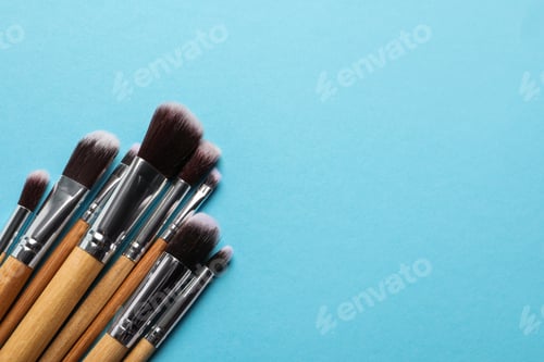 Preview: Different makeup brushes on light blue background, flat lay. Space for text
