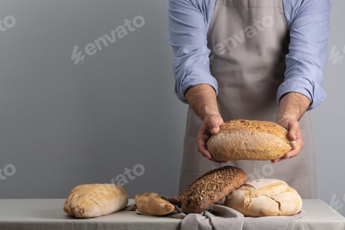 Preview: Baker holding freshly baked bread over table with free space