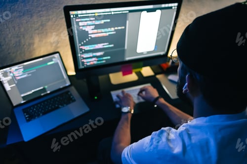 Preview: Young man mobile developer writes program code on a computer, programmer work in home office.
