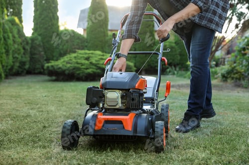 Preview: Man pulling starter cord of lawn mower in garden, closeup