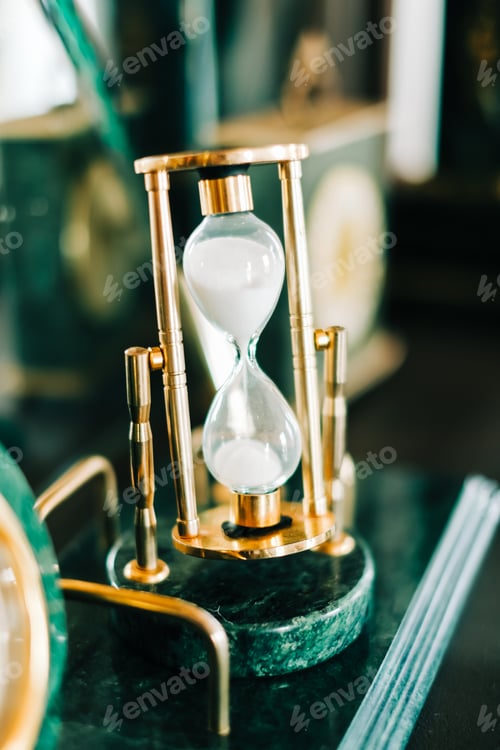 Preview: Vintage golden hourglass on the table, closeup.