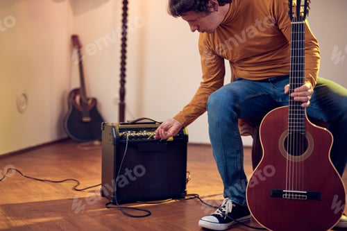 Preview: Male Musician Playing Acoustic Guitar On The Amplifier In Retro Vintage Room.