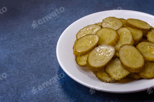 Preview: Delicious salted, canned cucumbers cut into slices on a white ceramic plate