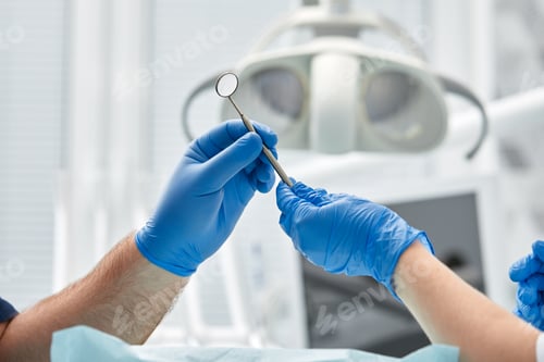 Preview: Close-up of the hands of a dentist and nurse surgeon over an operating room during a dental implant