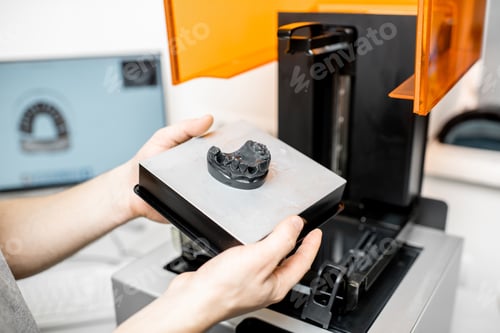Preview: Dental technician removing jaw model from a 3d printer