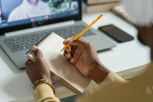 Preview: Hands of young African student with pencil over notepad