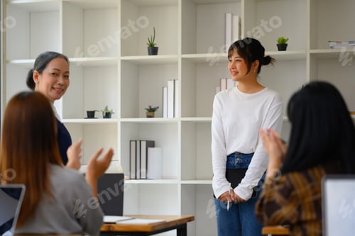Preview: Smiling Asian student woman having presentation while her classmates giving applause