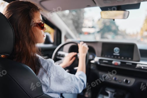 Preview: Driving woman with hands on steering wheel, focusing on car's dashboard screen