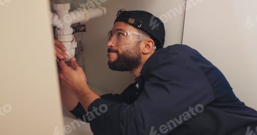 Preview: Plumber, man and pipe inspection in kitchen with safety for home maintenance or fixing leak by sink